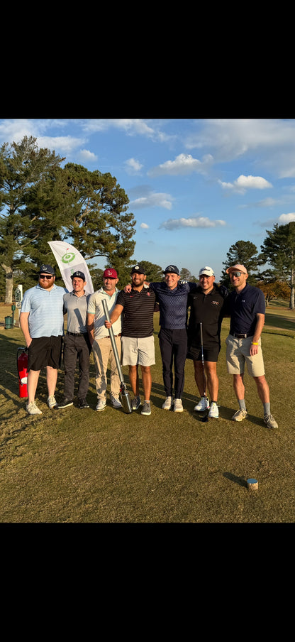 Group of golfers at On-Brand tournament posing on a golf course with a clear sky.