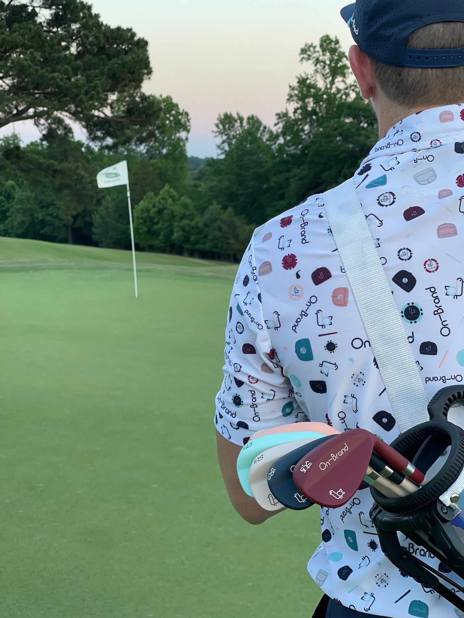 On-Brand Golf founder walking toward the pin at sunset with a fan of colorful Phoenix Wedges in his bag – On-Brand Golf