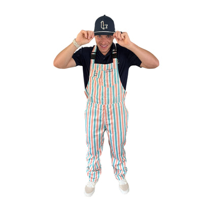 Golfer in On-Brand Golf Pair-a-Keets peach, seafoam, and cream striped bib overalls tipping a navy seagull cap, front view