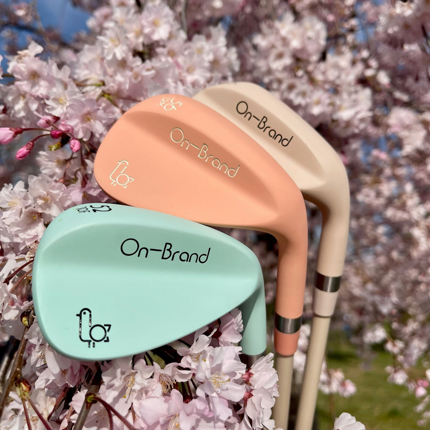 Three Phoenix Wedges — seafoam, peach, cream — against pink cherry blossom backdrop