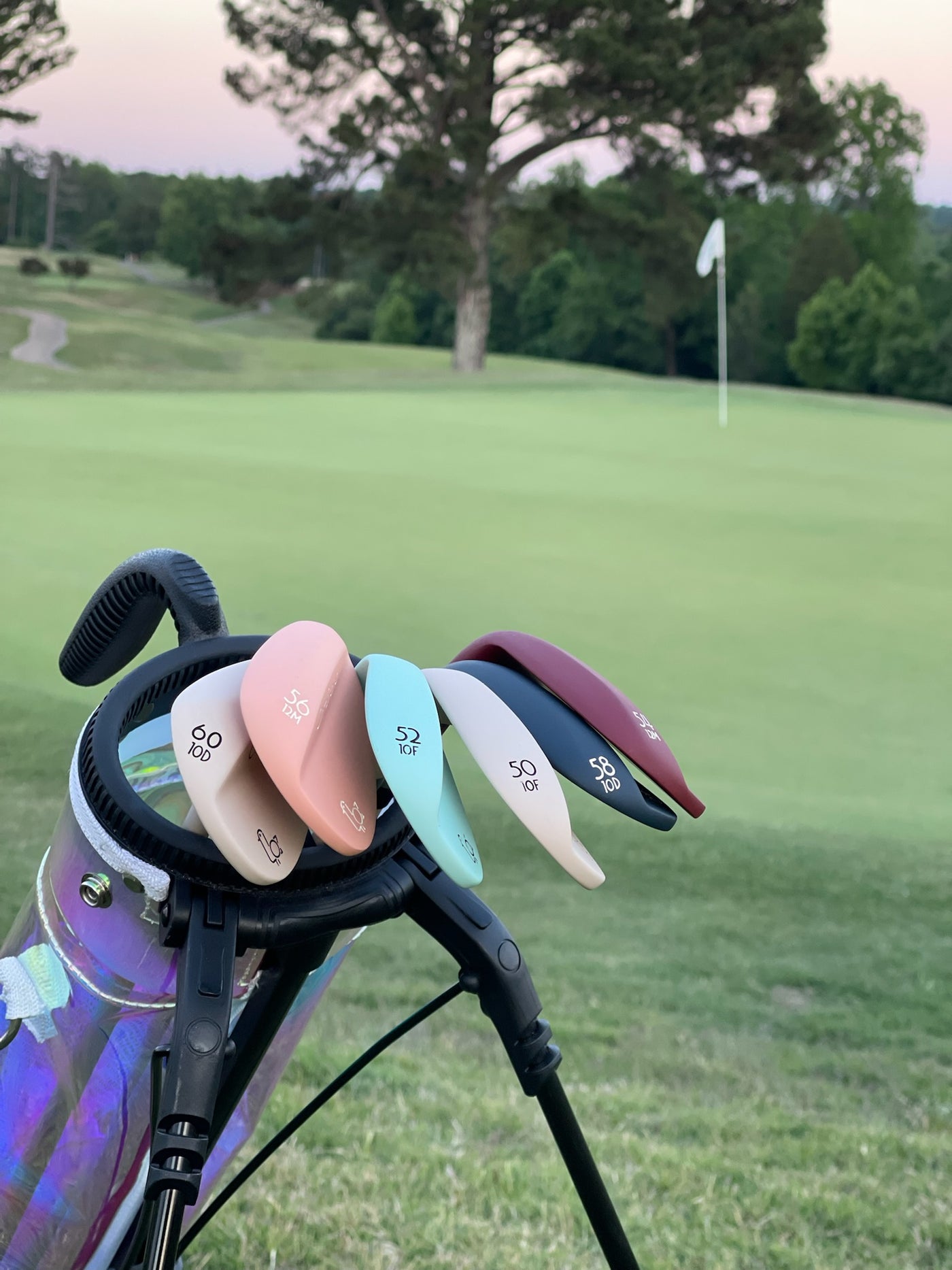 Phoenix Wedges fanned across a golf bag at sunset — cream, peach, seafoam, navy, and burgundy — with the green and pin flag behind – On-Brand Golf