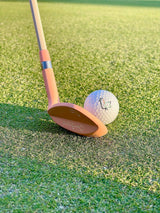Peach Phoenix Wedge soled behind an On-Brand logo golf ball on the green – On-Brand Golf