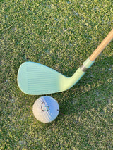 Seafoam Phoenix Wedge at address behind an On-Brand logo golf ball on the green – On-Brand Golf