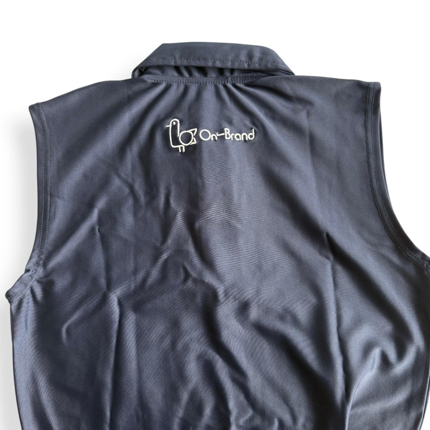 Back of a women's navy sleeveless golf polo with On-Brand bird logo – On-Brand Golf