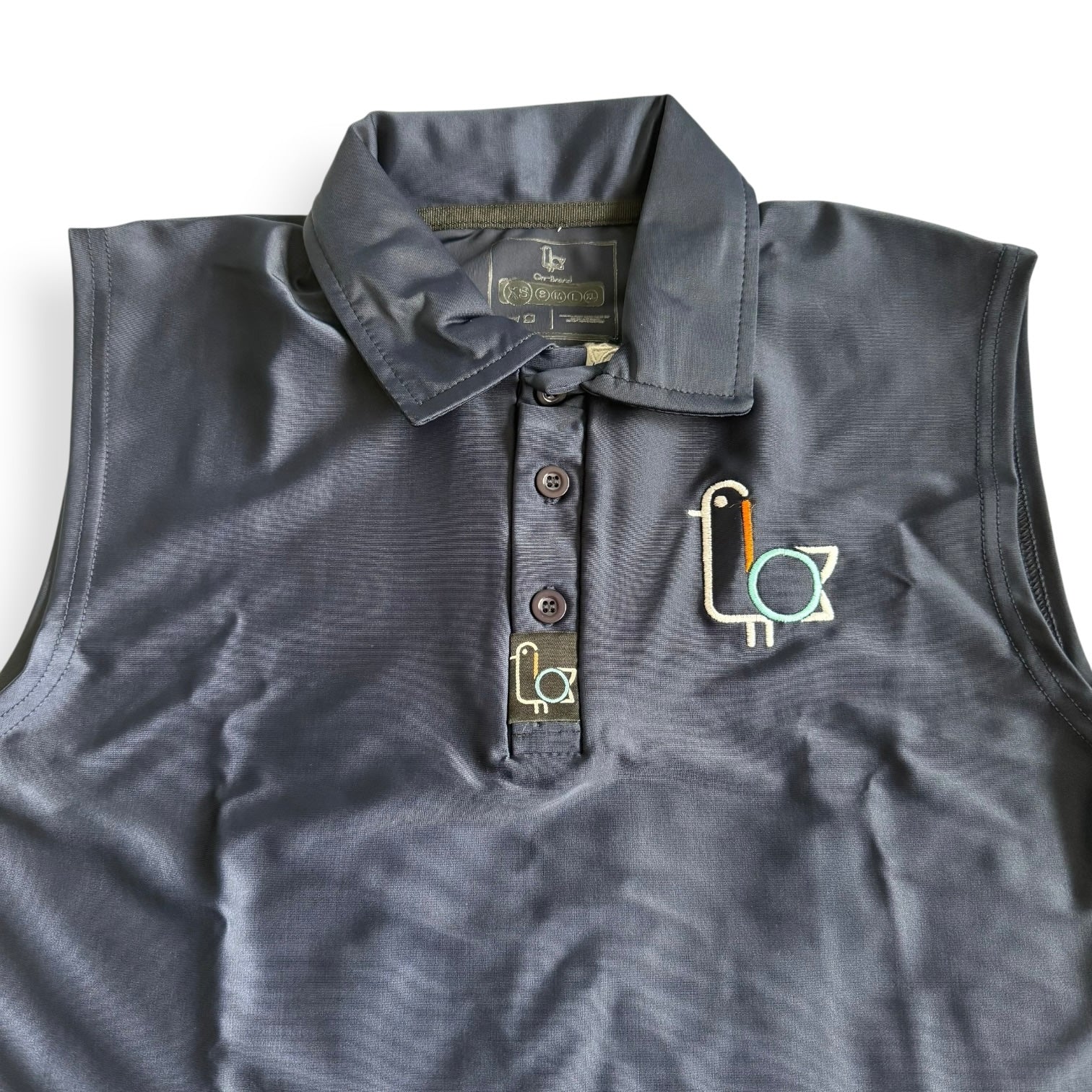 Women's navy sleeveless golf polo with colorful bird crest, front – On-Brand Golf